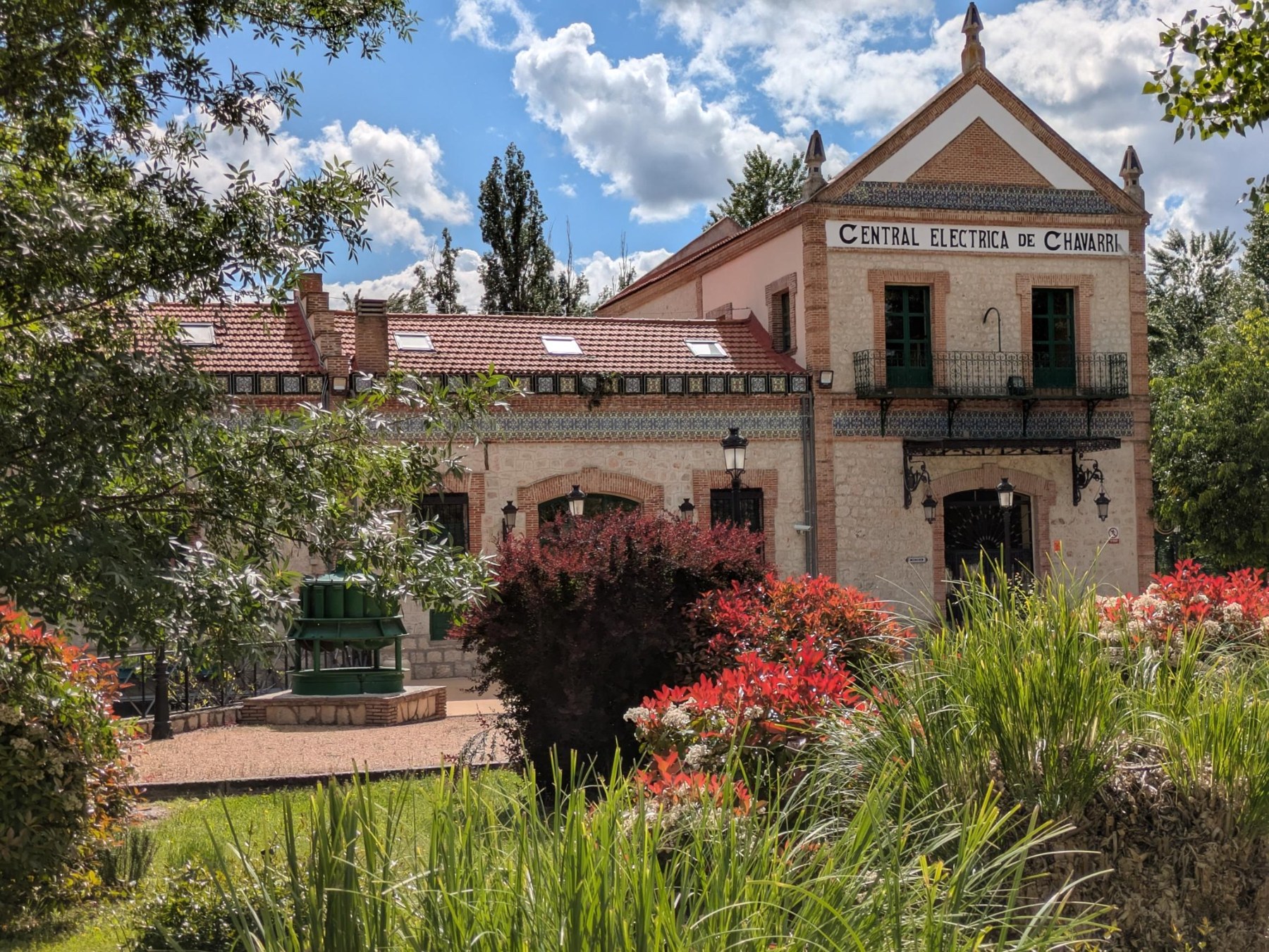Edificio histórico de Agua de Carabaña rodeado de árboles y flores